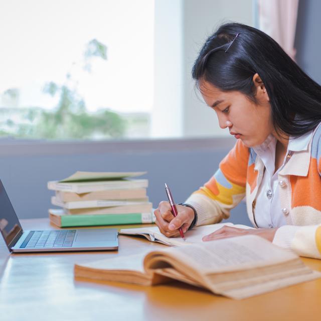 Young person studying from home with laptop and books